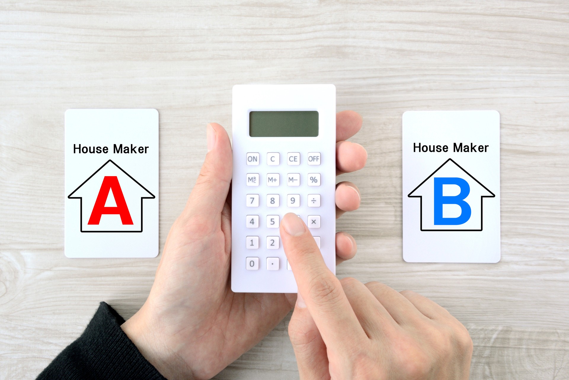 Human's hands using calculator to decide which housing company is better